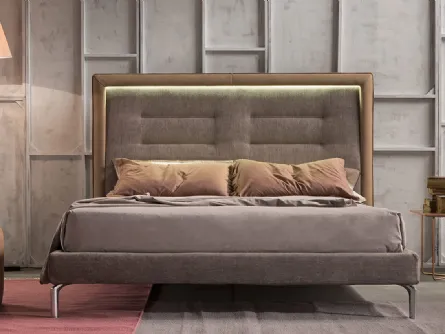Letto imbottito in tessuto accostato alla cornice in pelle della testiera trapuntata e arricchita dalla luce a LED Queen di Novaluna