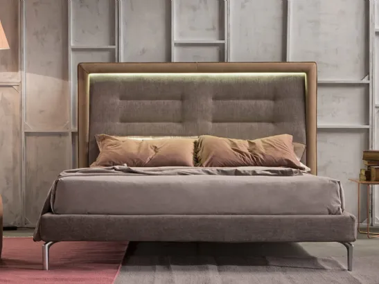 Letto imbottito in tessuto accostato alla cornice in pelle della testiera trapuntata e arricchita dalla luce a LED Queen di Novaluna